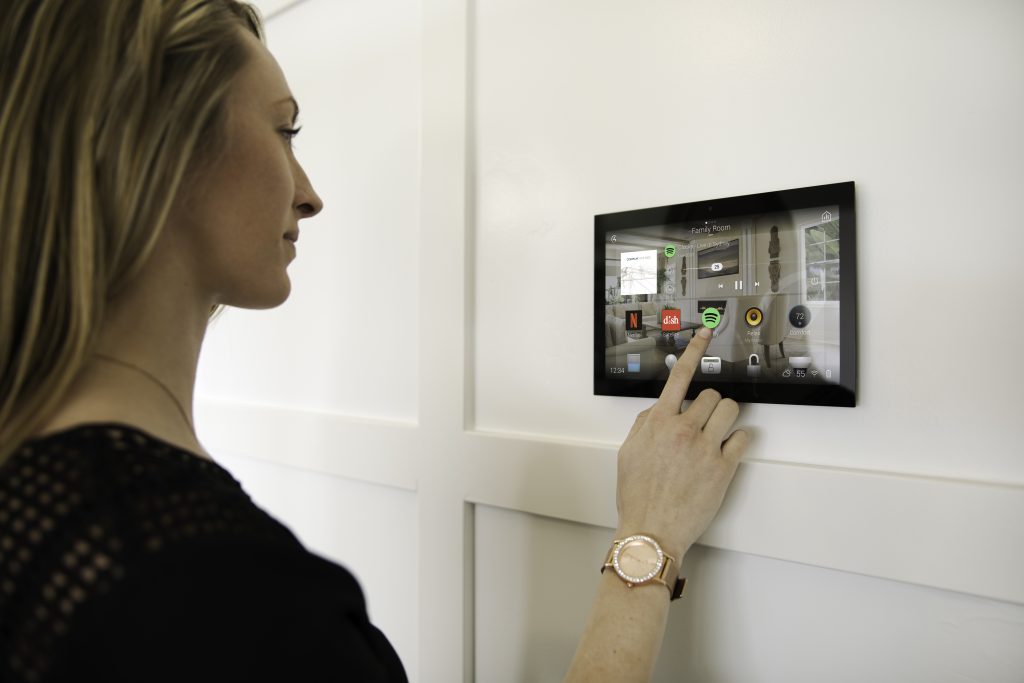Smarthome Das Bild zeigt eine Frau an einem Bedienelement von Control4 zu Steuerung von einem Haus oder einer Wohnung.