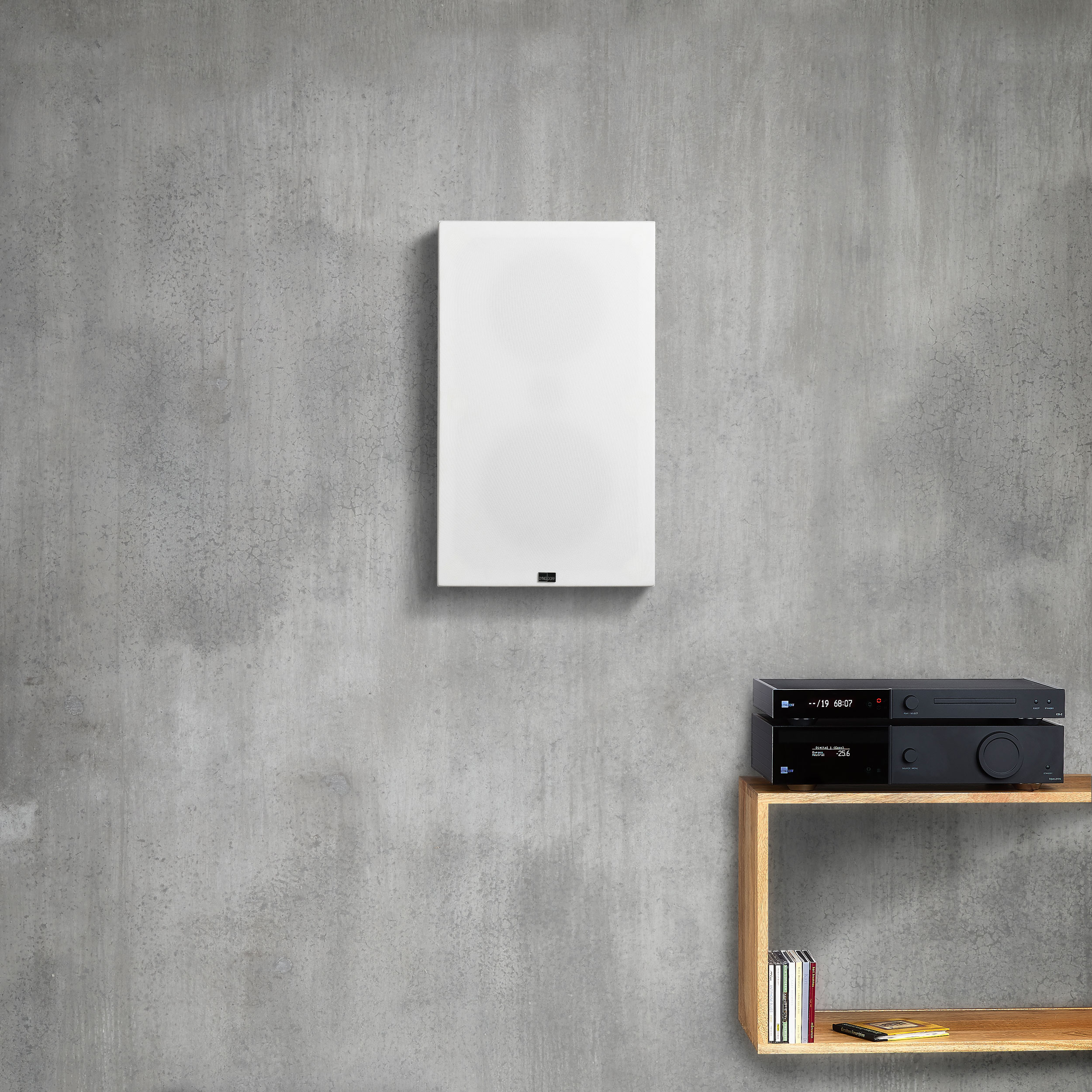 Lyngdorf FR-1 Wandlautsprecher Weiß mit Abdeckung auf dem grauer Wand 2500x2500
